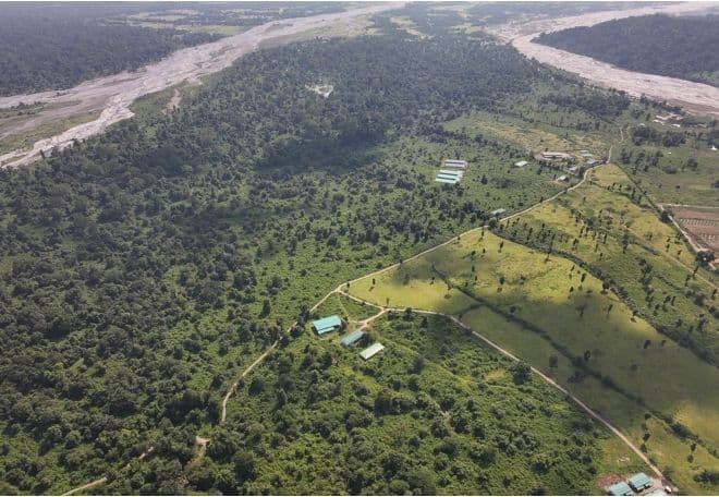 Samrang project landscape with forest, wide riverbed, green-roof buildings, and access tracks.